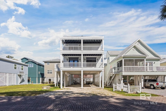 coastal inspired home featuring a carport, stairway, decorative driveway, and fence