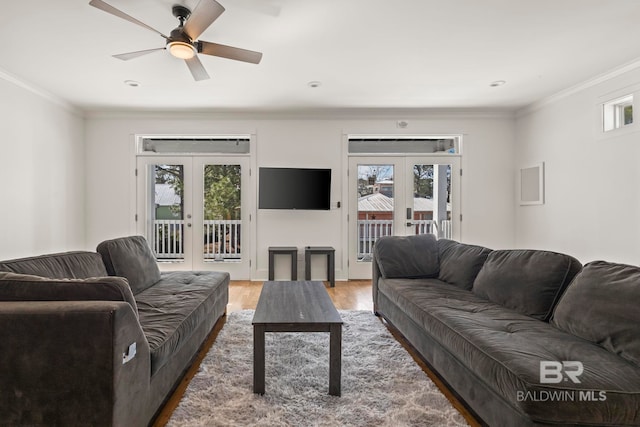 living area featuring a ceiling fan, wood finished floors, crown molding, and french doors