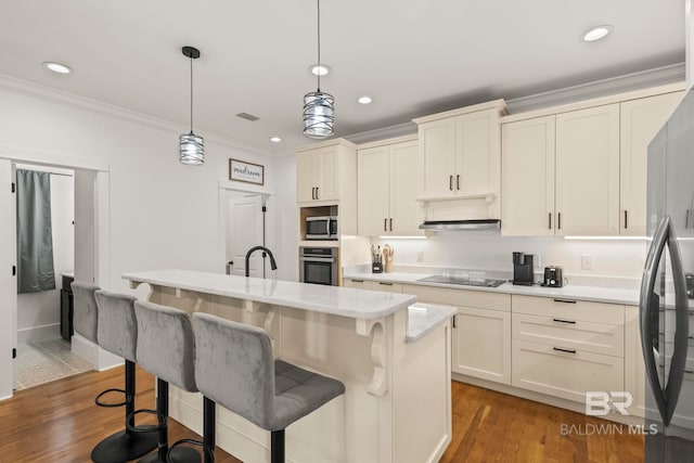 kitchen featuring visible vents, ornamental molding, light countertops, appliances with stainless steel finishes, and a kitchen breakfast bar