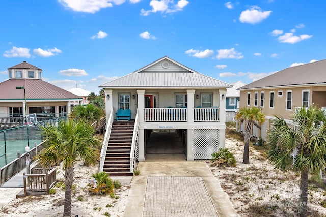 446 Harbor Light Cir, Gulf Shores, AL 36542 - raised beach house with driveway, a porch, metal roof, fence, and stairs