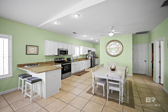 446 Harbor Light Cir, Gulf Shores, AL 36542 - kitchen featuring stainless steel appliances, a sink, white cabinets, a kitchen breakfast bar, and light tile patterned floors