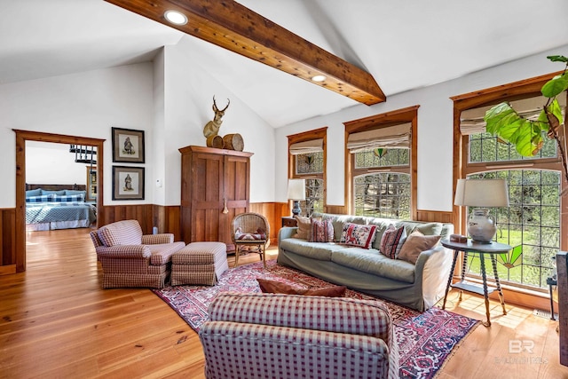 living room featuring a wainscoted wall, vaulted ceiling with beams, light wood-style flooring, and wooden walls