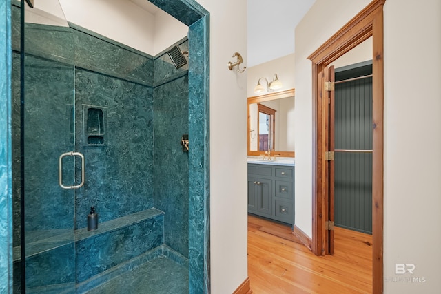 bathroom featuring wood finished floors, a stall shower, and vanity