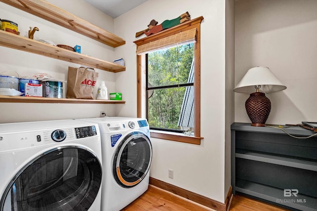 laundry area featuring washer and clothes dryer, light wood-style floors, laundry area, and baseboards