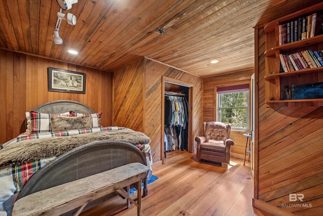 bedroom with a closet, wooden walls, wooden ceiling, and light wood-style floors