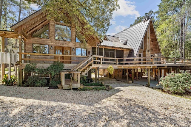 rear view of property featuring a wooden deck, a sunroom, and metal roof