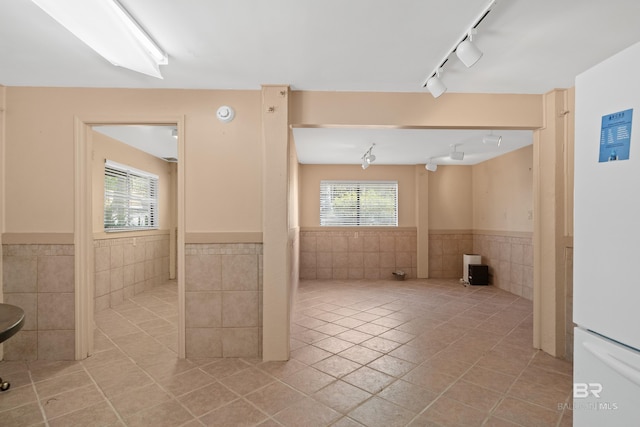 interior space featuring a wainscoted wall, a wealth of natural light, light tile patterned floors, and freestanding refrigerator