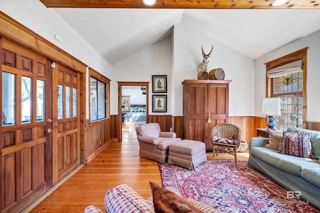 living room featuring a wealth of natural light, vaulted ceiling, and wainscoting