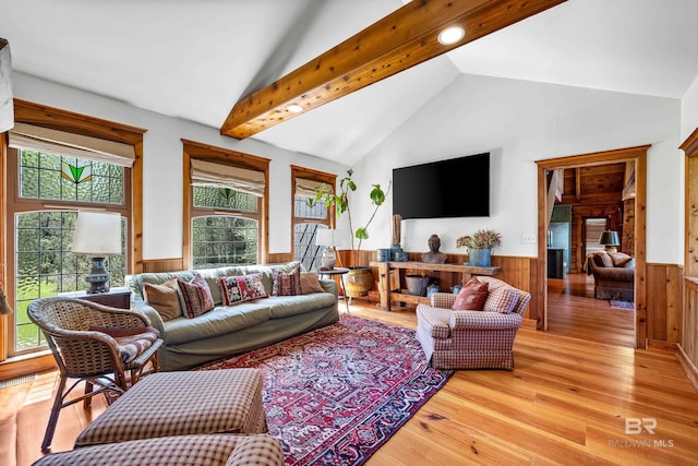 living room with high vaulted ceiling, beam ceiling, wooden walls, wainscoting, and light wood-style flooring