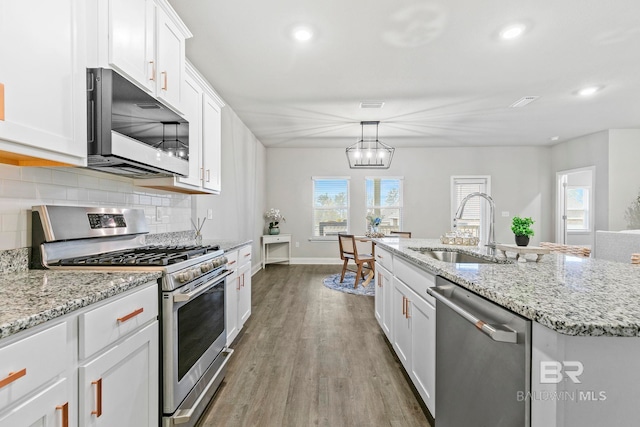 kitchen featuring a kitchen island with sink, white cabinets, sink, decorative backsplash, and stainless steel appliances