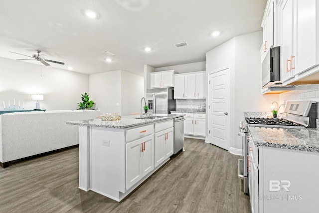 kitchen featuring white cabinets, stainless steel appliances, and an island with sink