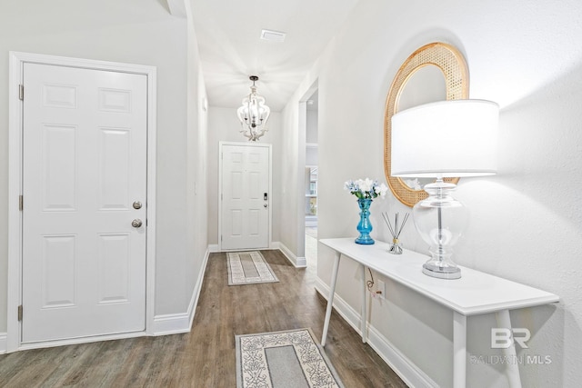 foyer with dark wood-type flooring and a notable chandelier