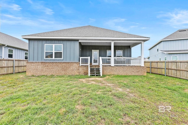 rear view of house featuring a lawn and a porch