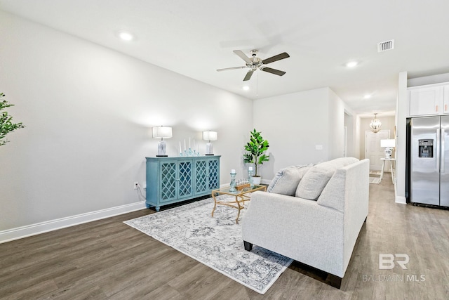 living room featuring dark hardwood / wood-style flooring and ceiling fan with notable chandelier