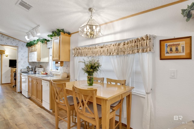 kitchen featuring white appliances, a textured ceiling, hanging light fixtures, and light brown cabinets