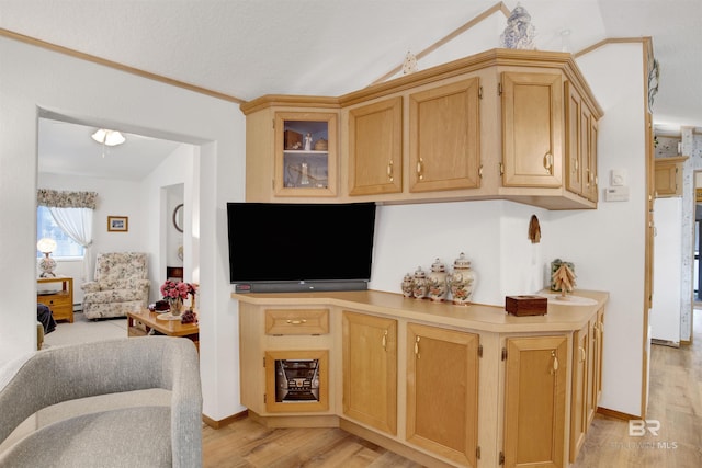 kitchen with light brown cabinetry, vaulted ceiling, and light hardwood / wood-style flooring