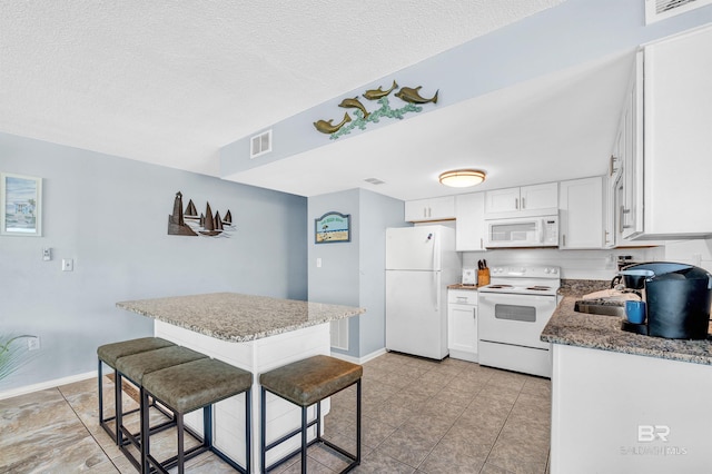 407 W Beach Blvd Unit 570, Gulf Shores, AL 36542 - kitchen featuring white appliances, white cabinets, baseboards, a textured ceiling, and stone countertops