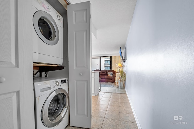 407 W Beach Blvd Unit 570, Gulf Shores, AL 36542 - laundry room featuring stacked washer / drying machine, light tile patterned floors, and baseboards