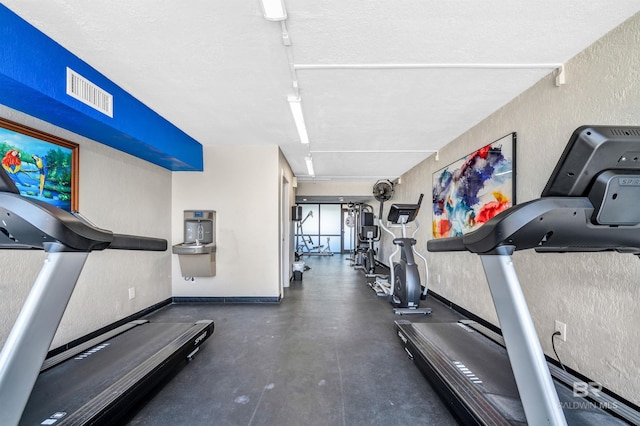 407 W Beach Blvd Unit 570, Gulf Shores, AL 36542 - gym with a textured wall, baseboards, and a textured ceiling