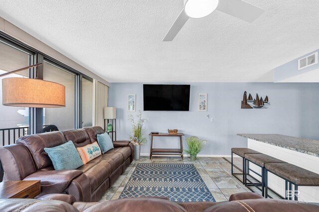 407 W Beach Blvd Unit 570, Gulf Shores, AL 36542 - living room featuring a ceiling fan, a textured ceiling, baseboards, and healthy amount of natural light