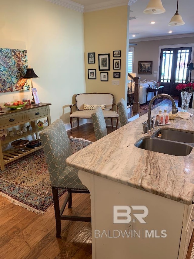 40 Bay Pointe Ct, Fairhope, AL 36532 - kitchen featuring crown molding, a sink, light stone countertops, wood-type flooring, and pendant lighting