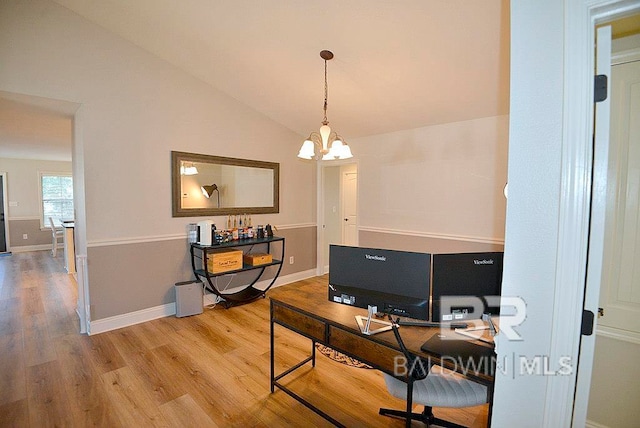 office with hardwood / wood-style floors, vaulted ceiling, and an inviting chandelier