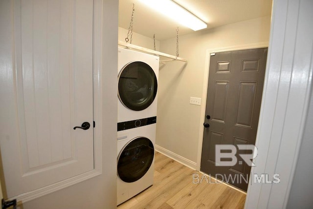 clothes washing area featuring stacked washer / dryer and light wood-type flooring