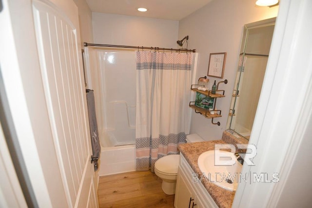 full bathroom featuring shower / bath combo with shower curtain, wood-type flooring, vanity, and toilet