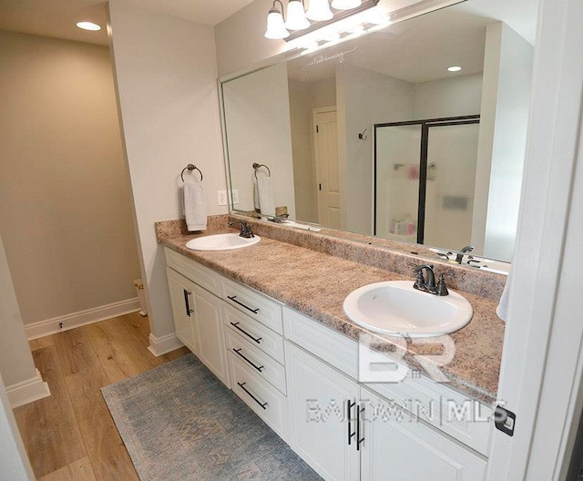 bathroom with walk in shower, vanity, and hardwood / wood-style flooring