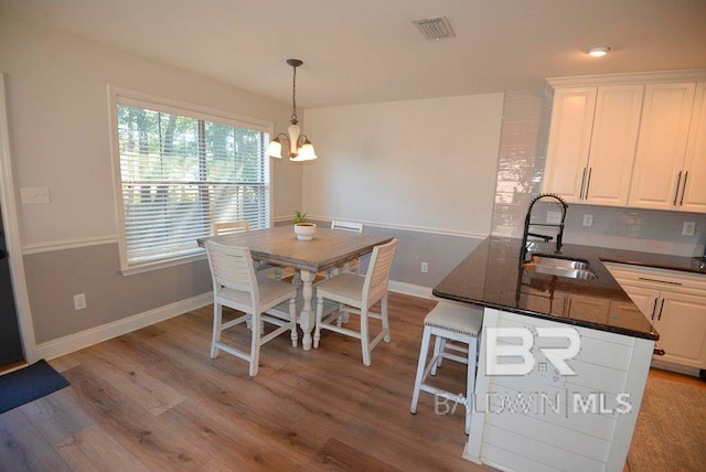 dining space featuring light wood-type flooring, a chandelier, and sink