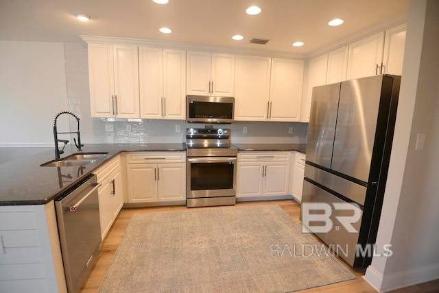 kitchen with stainless steel appliances, white cabinetry, sink, and decorative backsplash