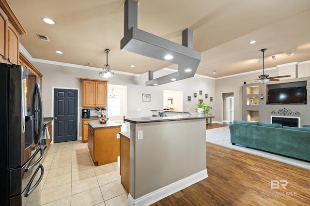 kitchen featuring stainless steel fridge with ice dispenser, ceiling fan, a kitchen island, and crown molding