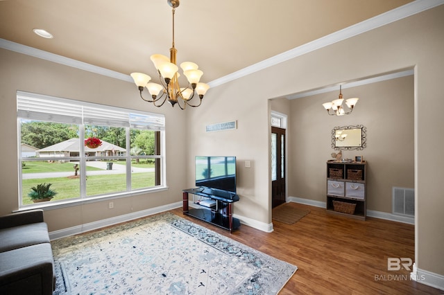 living room with wood-type flooring, ornamental molding, and a chandelier