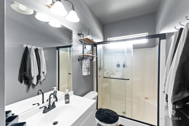 bathroom with toilet, an enclosed shower, and vanity