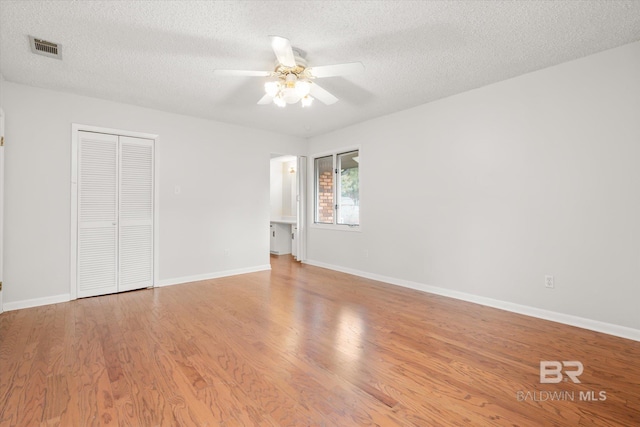 spare room with ceiling fan, a textured ceiling, and light hardwood / wood-style floors