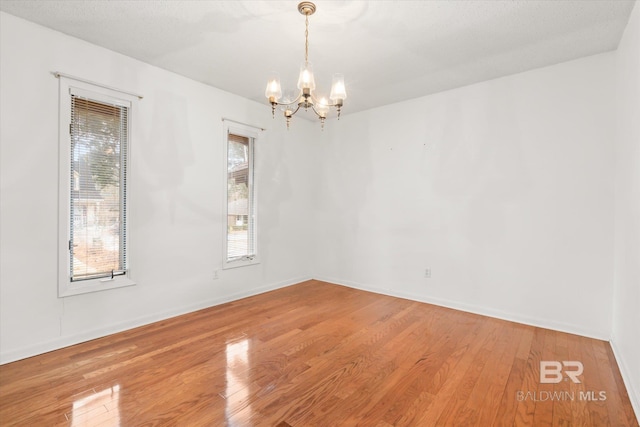 spare room featuring a chandelier and hardwood / wood-style floors