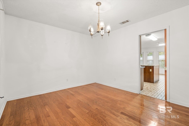 empty room with an inviting chandelier and light wood-type flooring