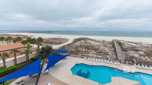 view of pool with a view of the beach, a water view, and a patio area