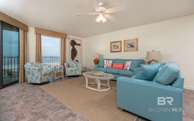 living room with ceiling fan and a textured ceiling