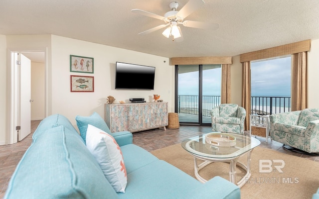 living room with ceiling fan and a textured ceiling