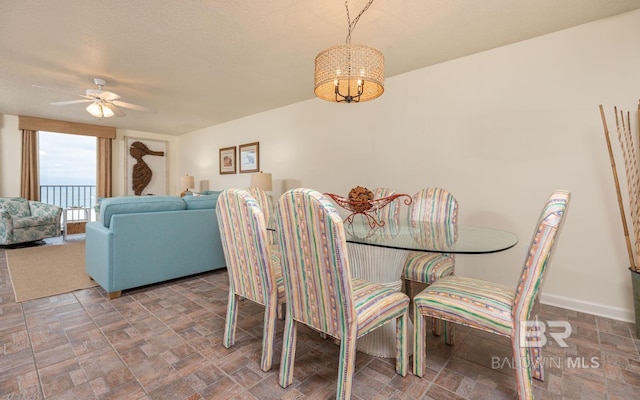 dining space featuring a textured ceiling and ceiling fan with notable chandelier