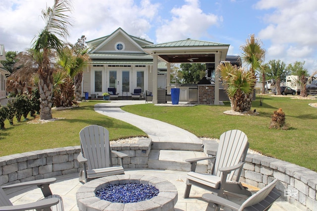 rear view of house featuring a gazebo, a yard, an outdoor fire pit, and french doors
