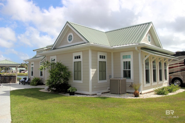 view of property exterior featuring cooling unit, a yard, a standing seam roof, and metal roof
