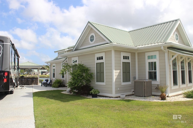 view of property exterior featuring a yard, central air condition unit, concrete driveway, a gazebo, and metal roof