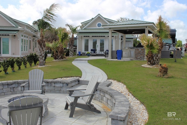 rear view of house with french doors, a gazebo, a patio area, an outdoor kitchen, and a yard
