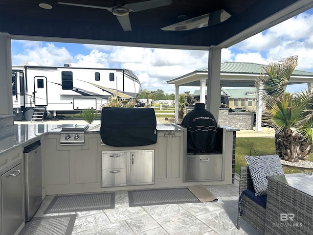 view of patio with an outdoor kitchen, a ceiling fan, a gazebo, and a grill