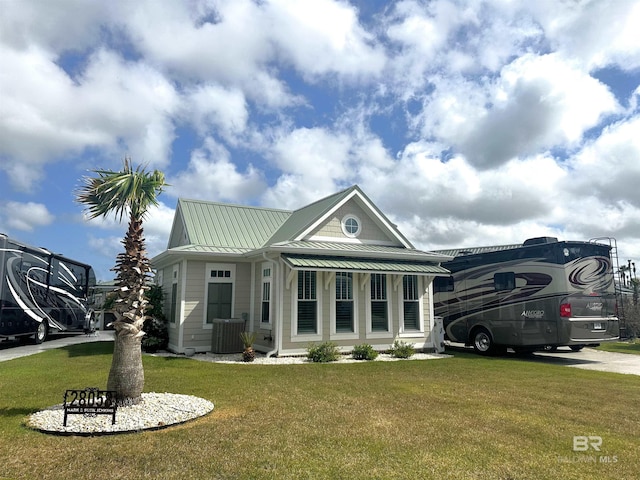 view of front of house with a standing seam roof, a front yard, central air condition unit, and metal roof