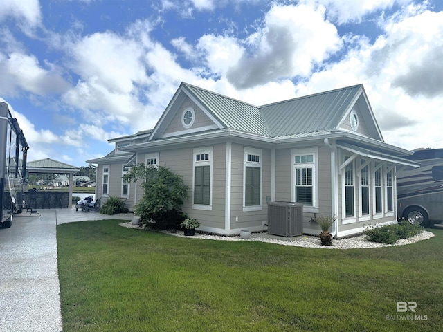 view of property exterior with a yard, central air condition unit, and metal roof