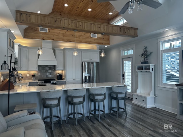 kitchen featuring visible vents, a peninsula, tasteful backsplash, appliances with stainless steel finishes, and custom exhaust hood