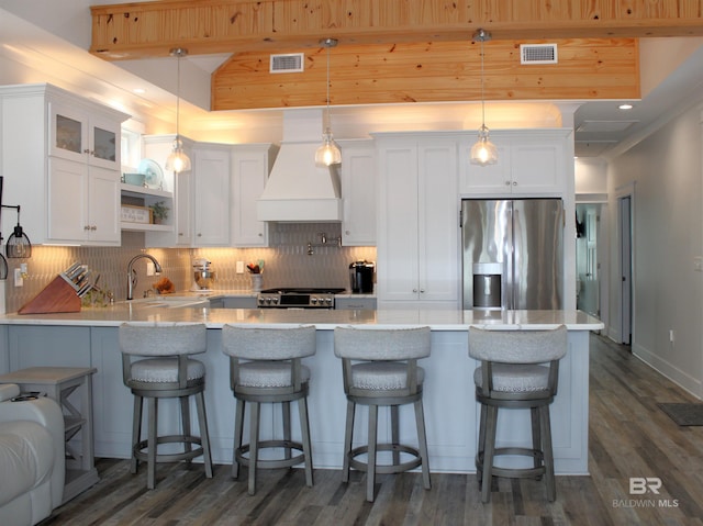 kitchen featuring a sink, stainless steel fridge with ice dispenser, custom range hood, backsplash, and visible vents